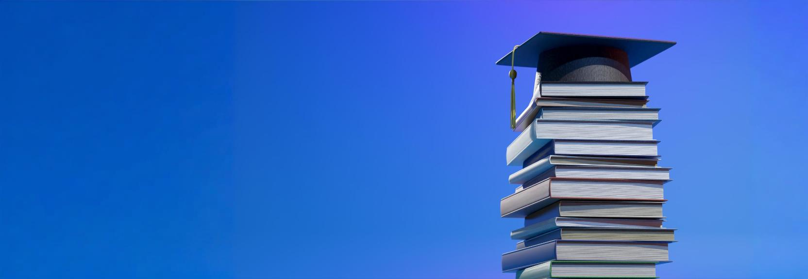 Stack of books with graduation cap on top